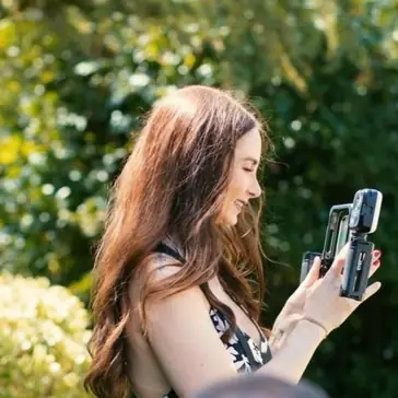 Rosie of Parker Rose Socials filming on a phone rig in a sunlit garden